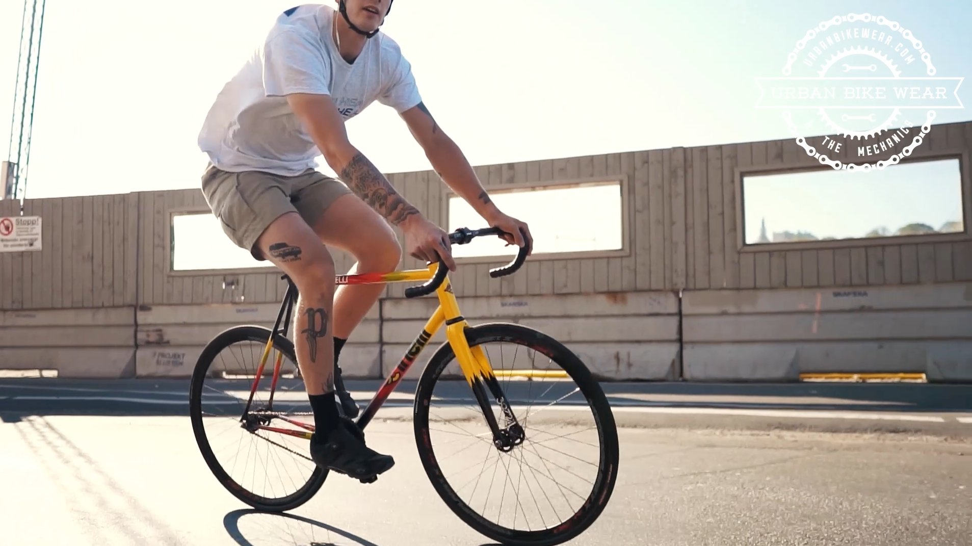 Indlæs video: En ung mand cykler på en bremsefri fixed gear-cykel fra mærket Cinelli gennem gaderne i solrige Stockholm, Sverige. Han har en white T-shirt og khakifarvede shorts på. Han har også en cykelhjelm og white hovedtelefoner på.